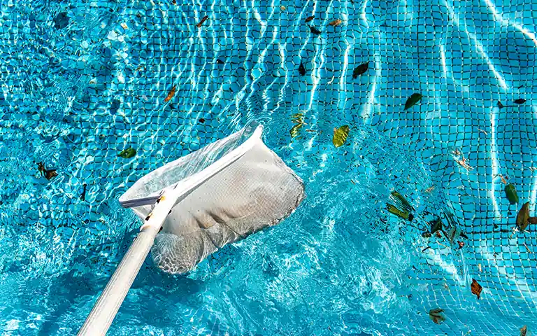 Tenerife Facility worker ensuring a clean and clear swimming pool.